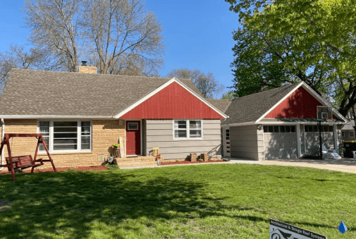 Charming suburban home with a red accent, spacious yard, and two-car garage.