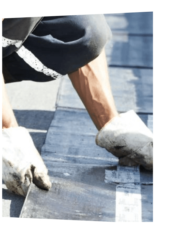 Worker applying roofing material with protective gloves