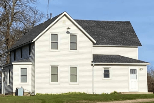 Charming two-story white house with dark roof under blue skies